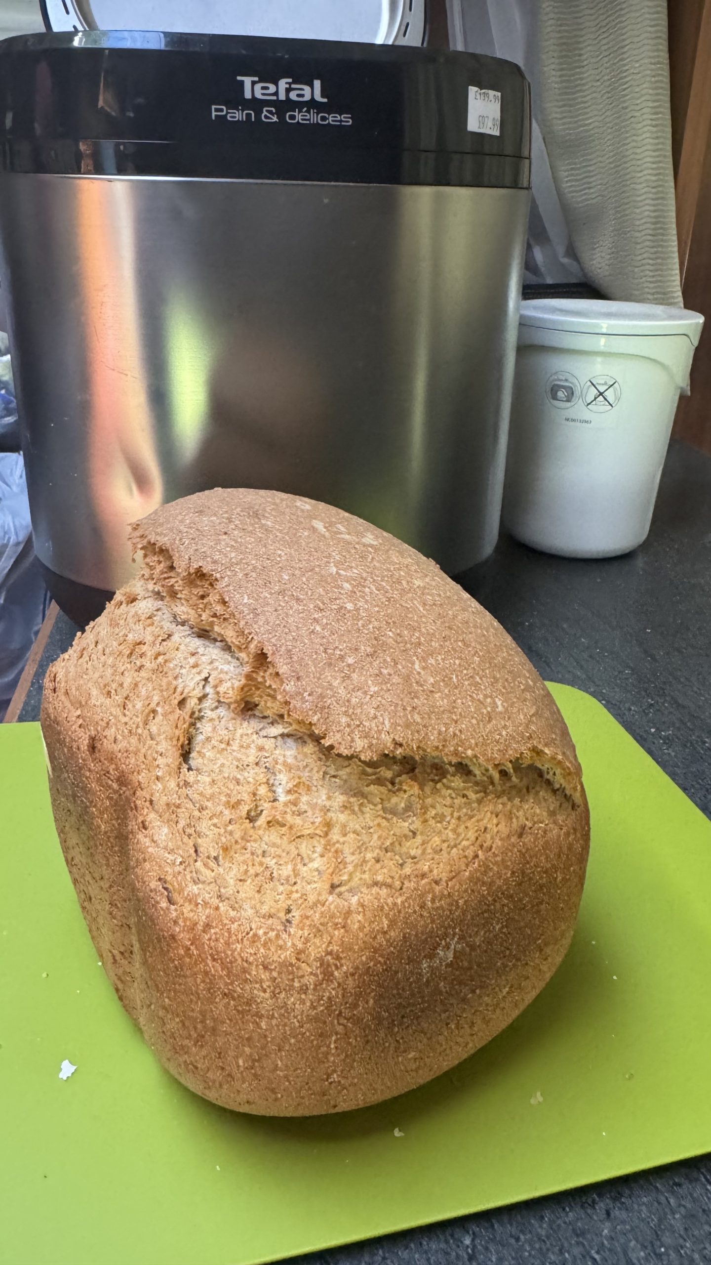 Loaf of freshly baked bread in front of a bread machine
