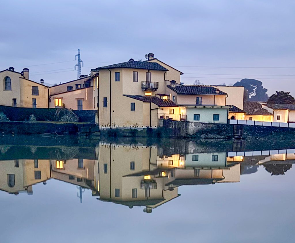 Old hotel reflected in evening light on the river Arno, Italy