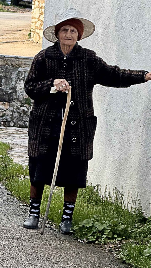 Elderly Albanian woman with large brimmed hat and walking stick