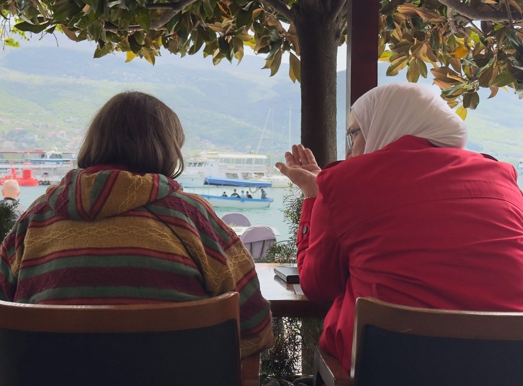 Two women of different faiths sat chatting in a cafe